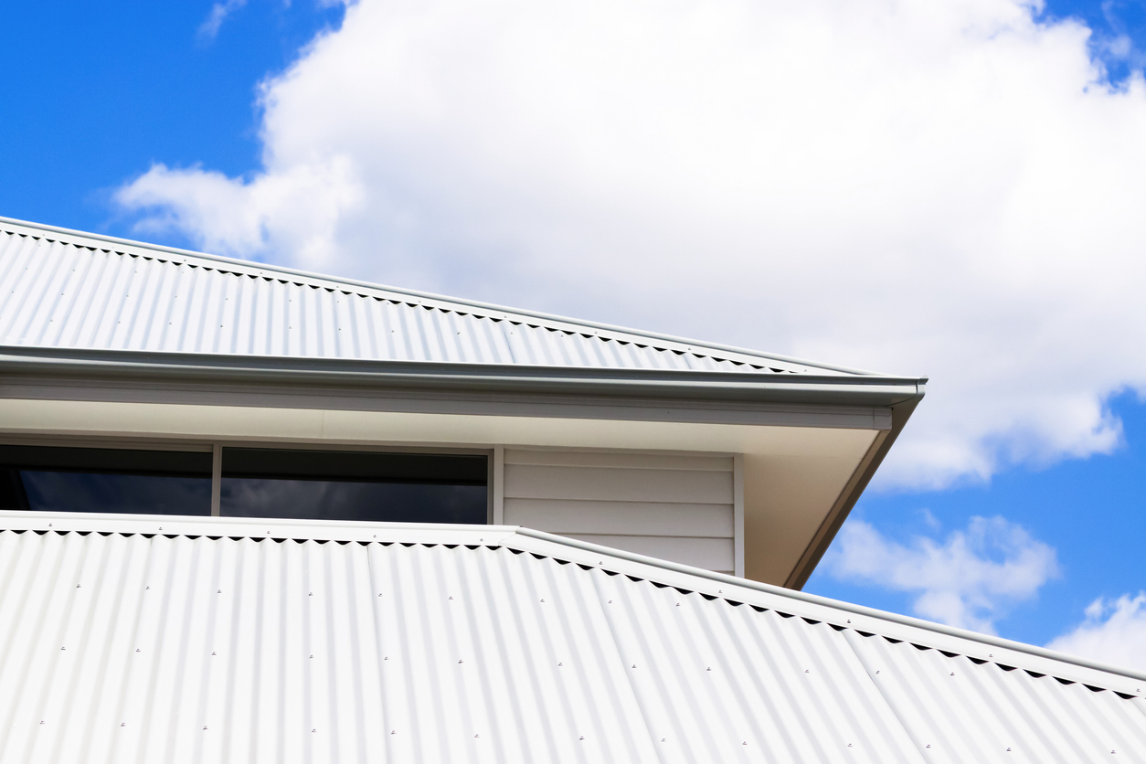 Modern house with white metal roof under blue sky