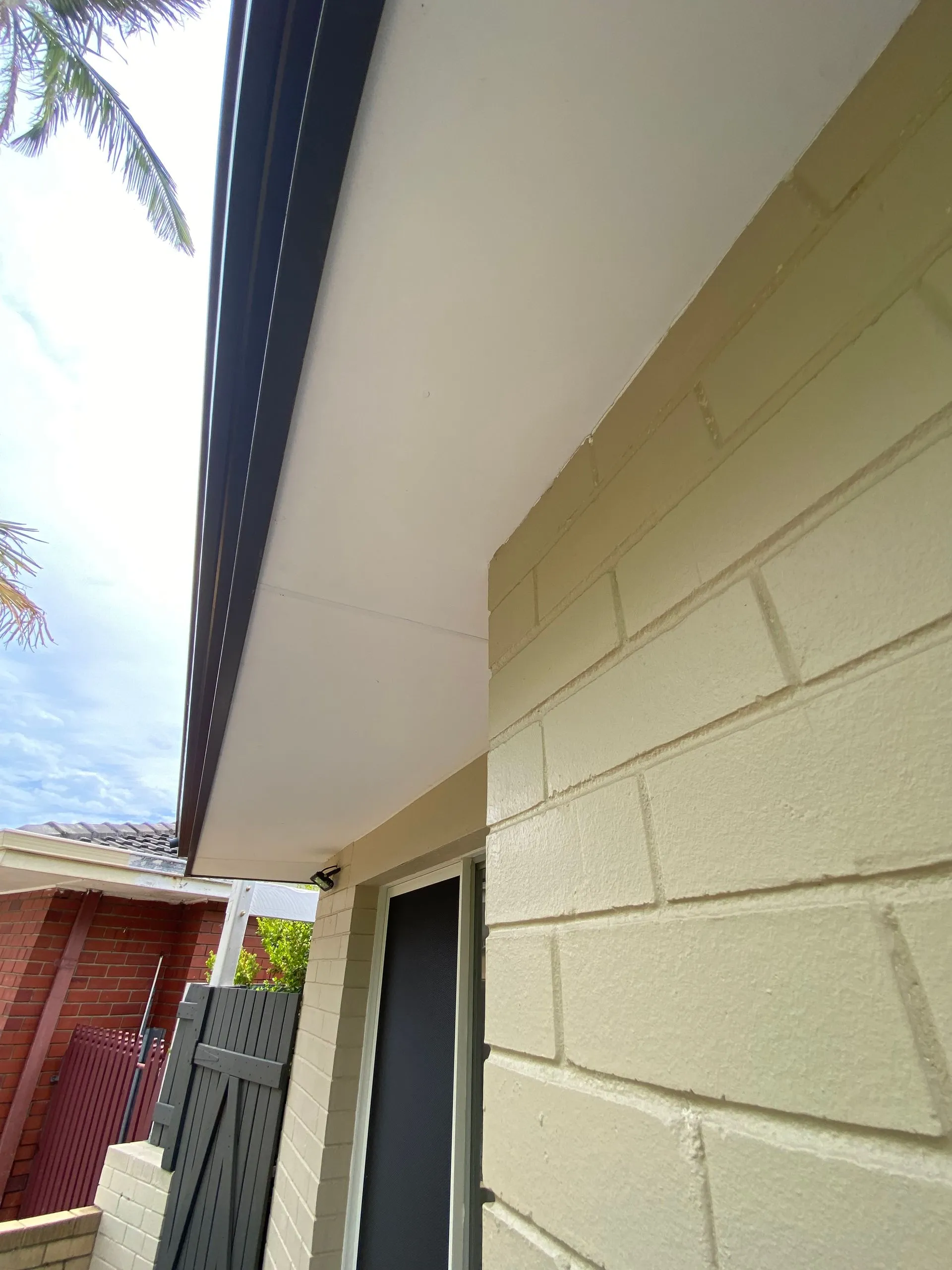 Cream brick house exterior with new eaves and colorbond guttering