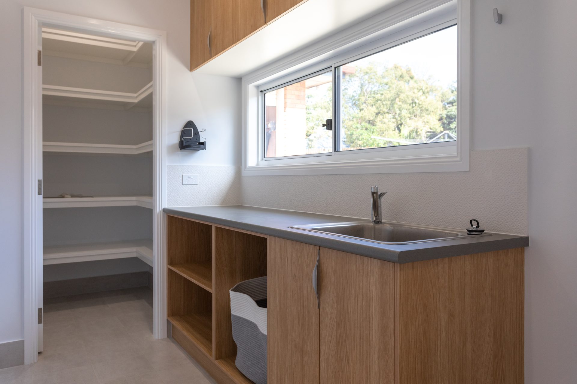 Modern laundry with timber cabinets and tiled splashback representing a compliant wet area renovation