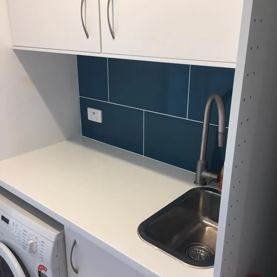 Modern laundry renovation with tile splashback and white cabinetry