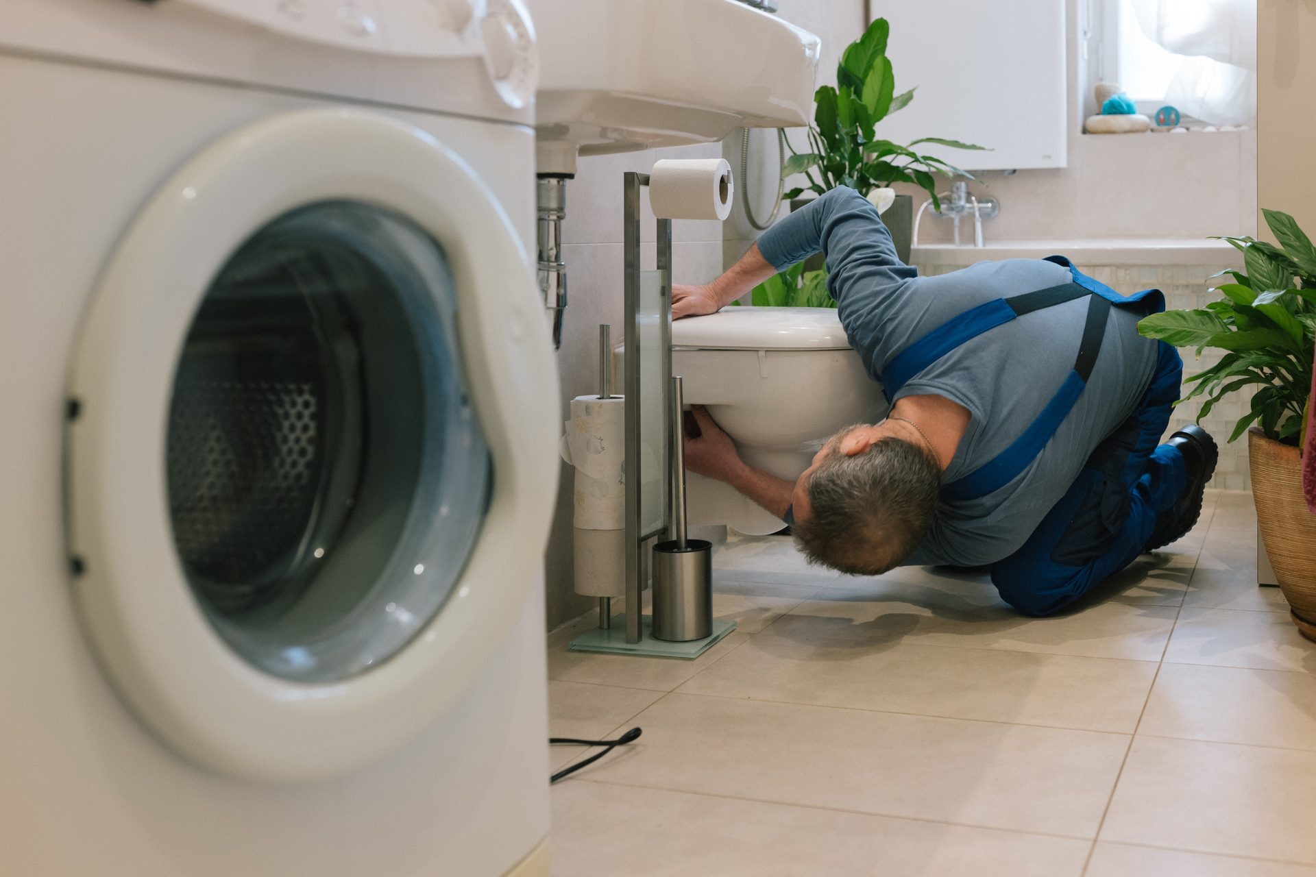 Plumber repairing toilet in modern bathroom demonstrating wet area plumbing integration